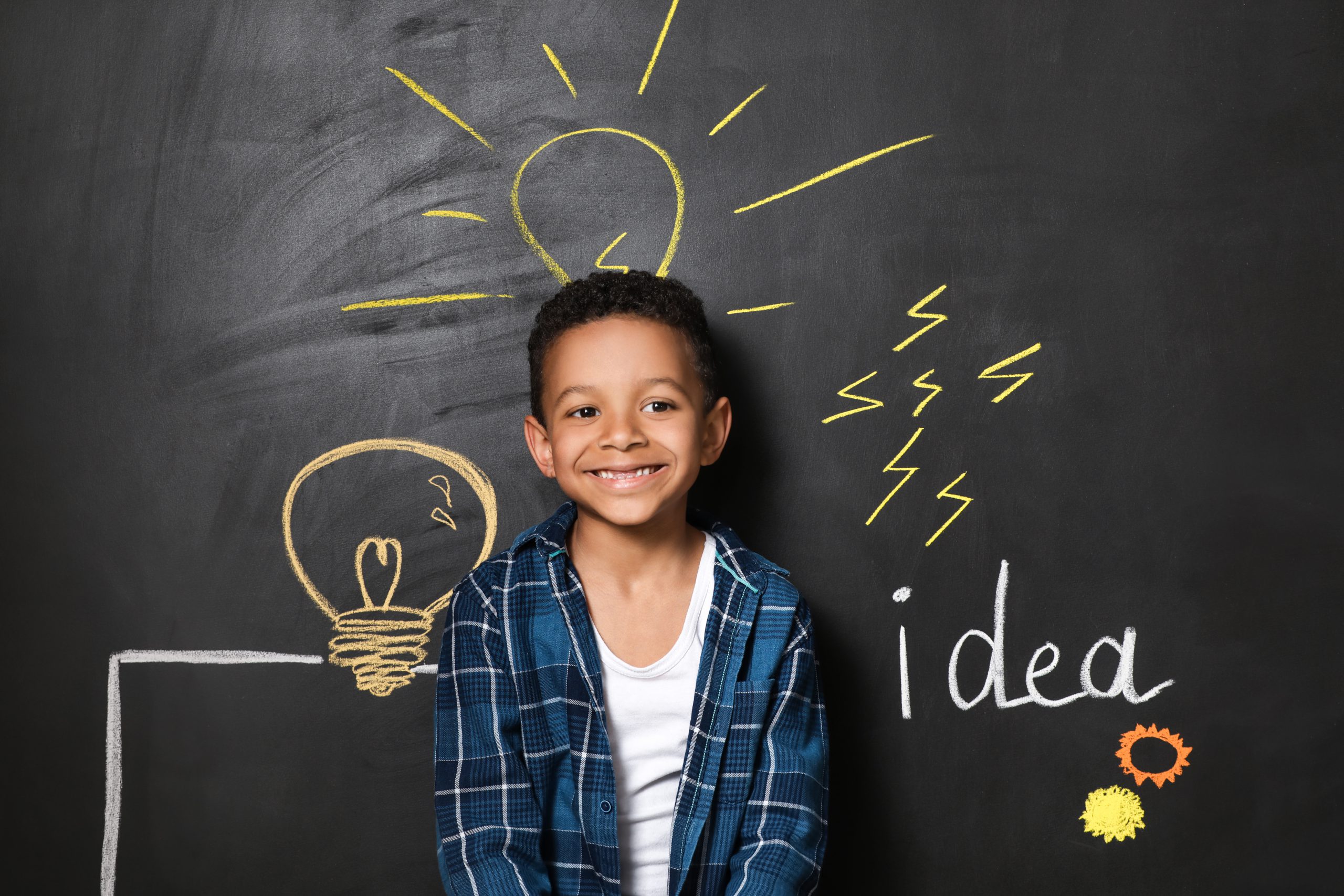 African-American boy near drawn light bulbs on dark wall