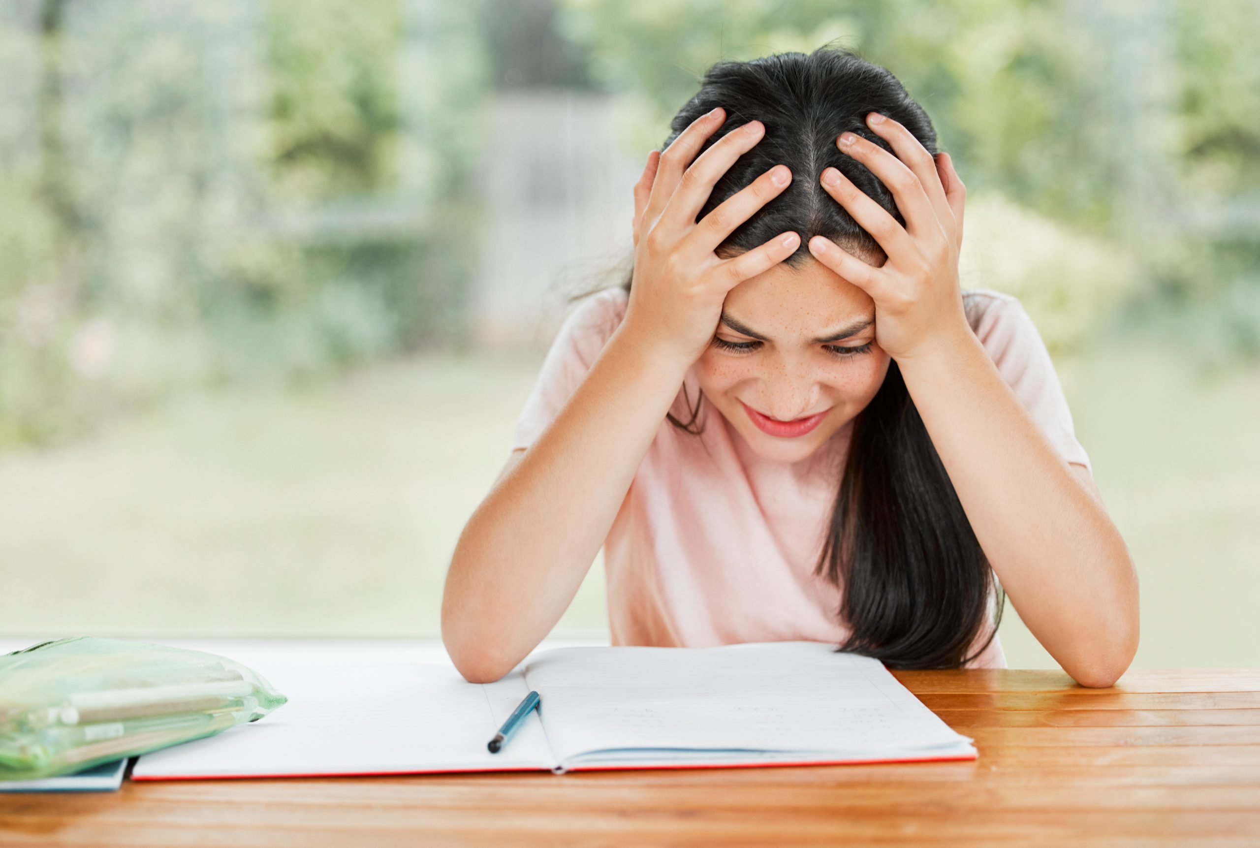 Stress, anxiety and overwhelmed with a little girl struggling with her studies, education and learning at home. Confused, frustrated and tired student having trouble with homework and study material.