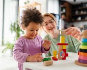 Mother looking at a child playing with an educational didactic t