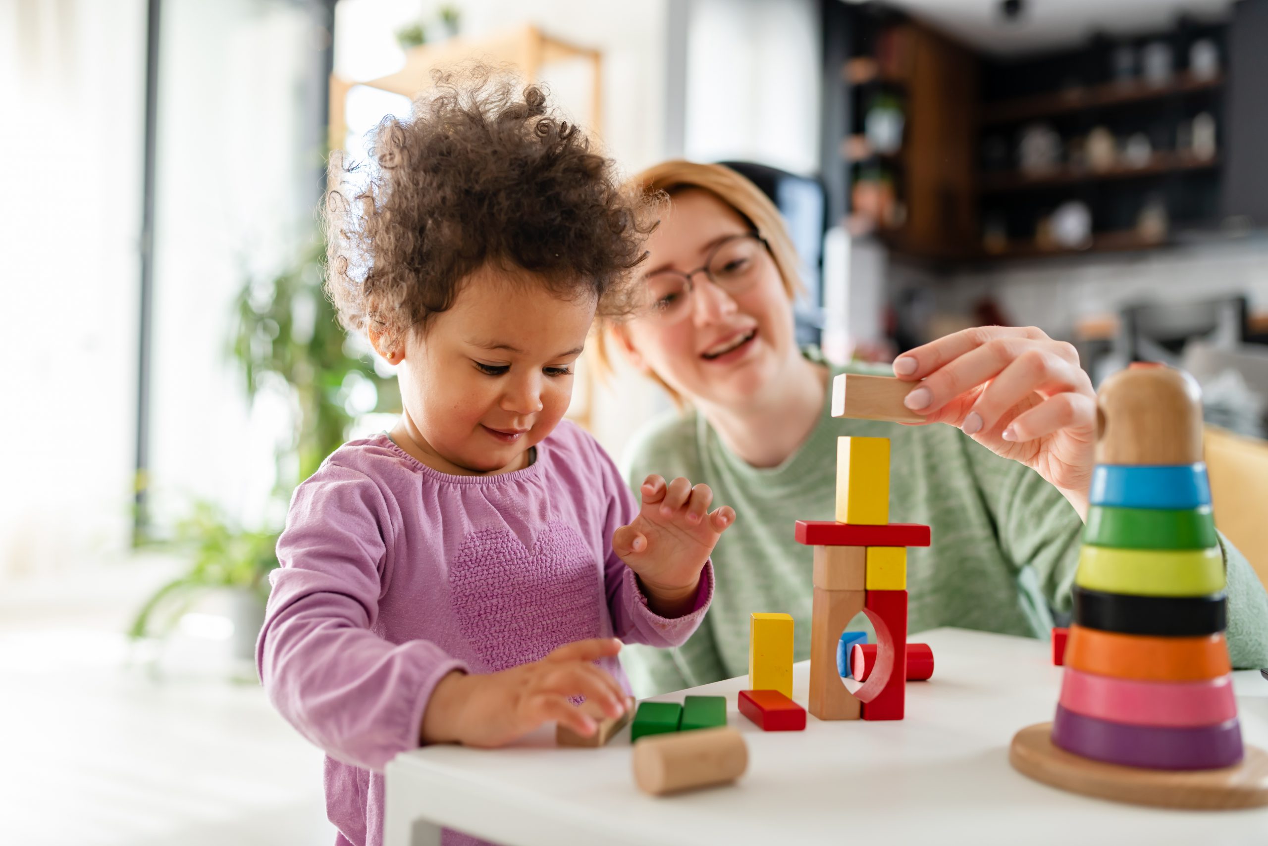 Mother looking at a child playing with an educational didactic t
